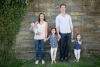 parents with 3 young children standing against ivy covered wall
