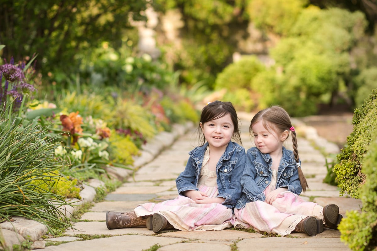 Two girls sit next to each other for photographing multiples session 
