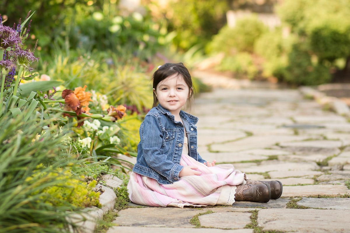 Little girl sits on sidewalk for photographing multiples session