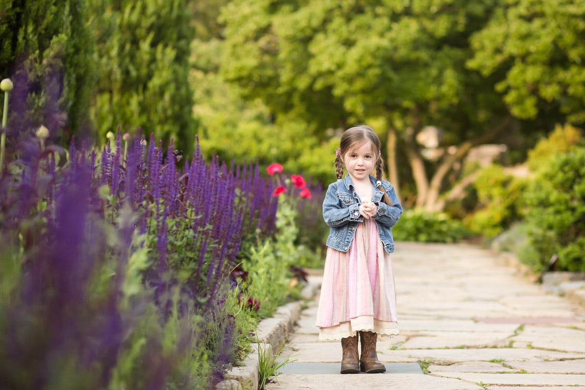 Little girl stands in beautiful garden for photographing multiples session