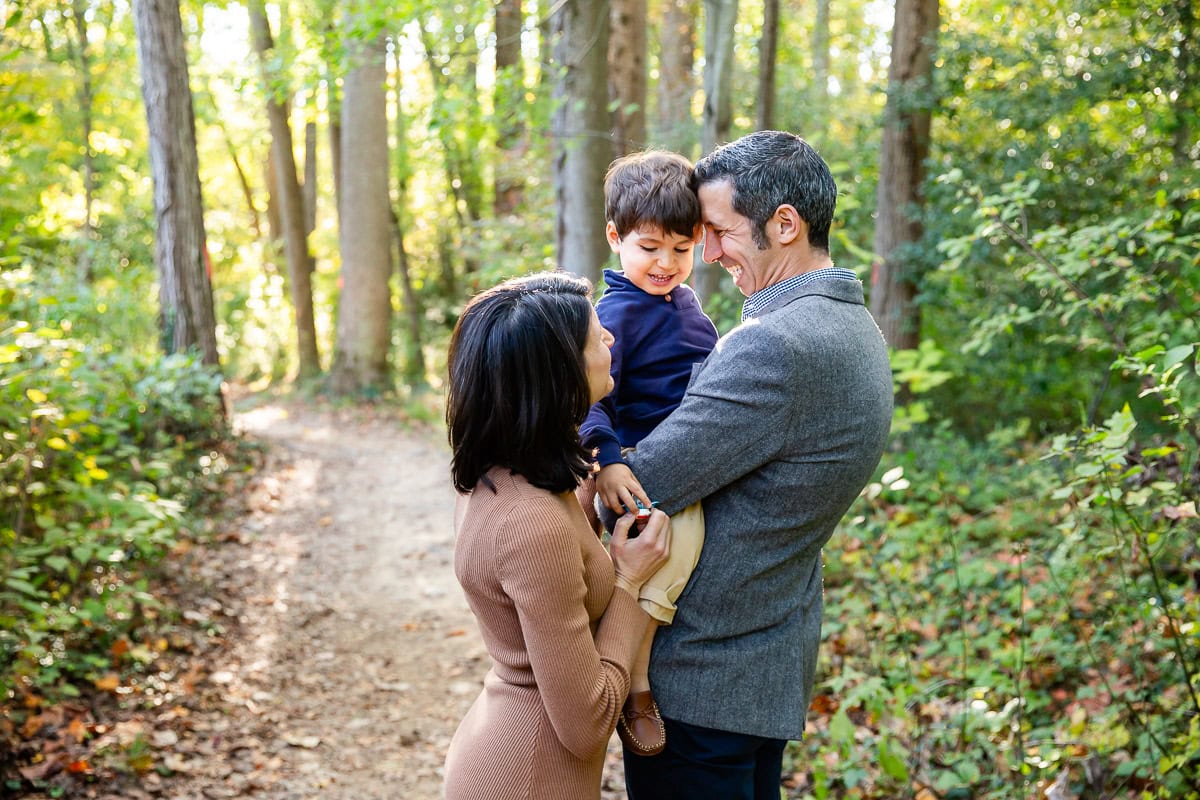 Mother and father hugging their young son in a photo taken along a wooded trail in McLean, VA. A Valentines Day family photo like this can be displayed as artwork in your home.