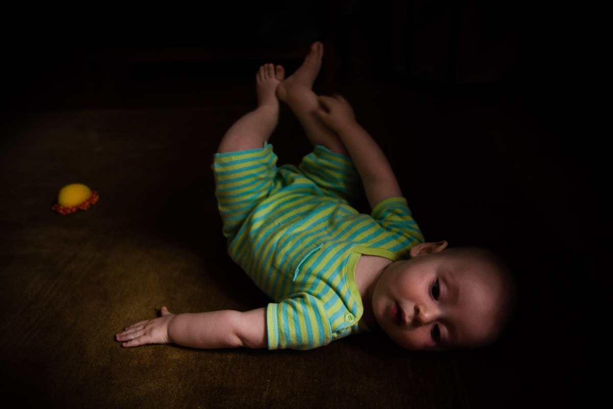 photo of baby boy lying on his back on the floor is an example of low light photography tips from Washington DC baby photographer Julie Kubal