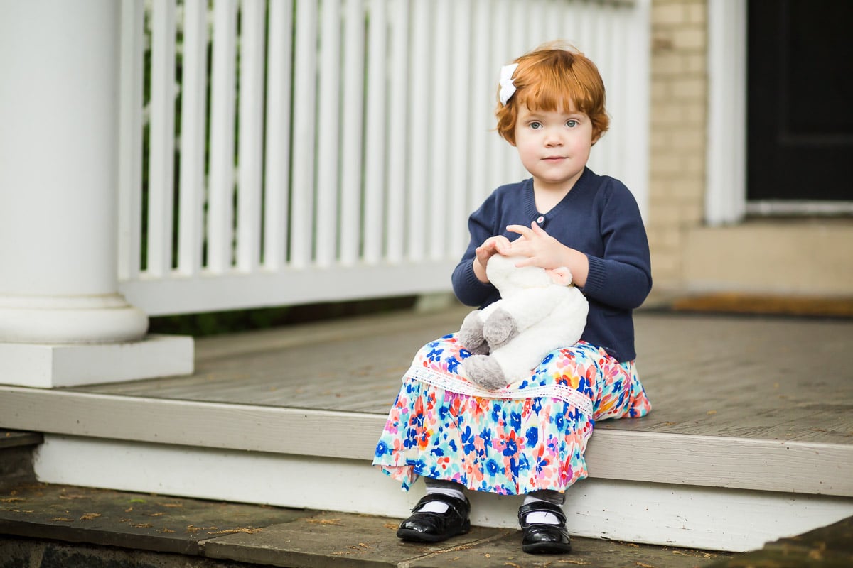 redheaded toddler girl sits on front steps of their home for Washington DC family photo shoot by Julie Kubal