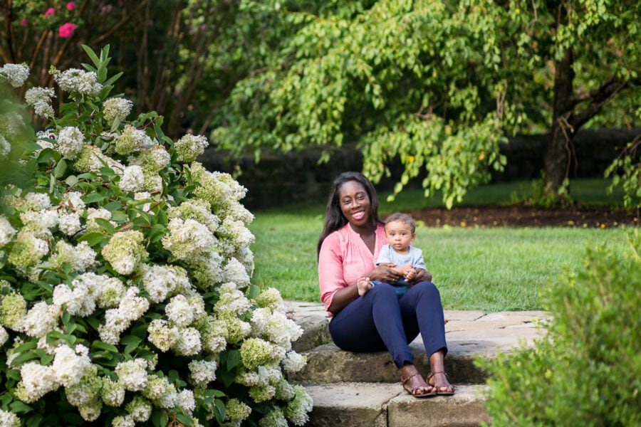 Young boy sits on hi mother's lap on stone steps in Bishop's Garden at National Cathedral for Mother & Child Photo Session.
