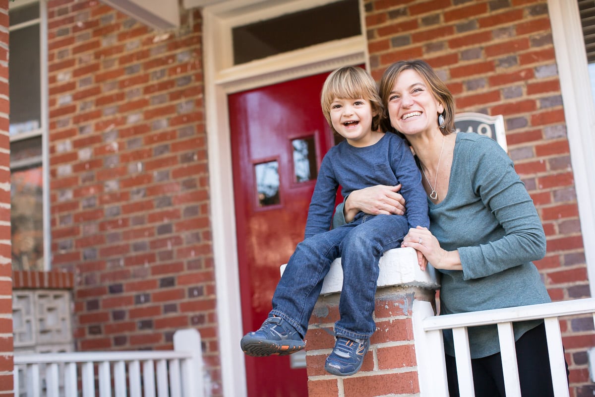 Don't forget to straighten up and declutter the front porch while cleaning up before an at-hom family photo session so your photographer can capture you and your kids in front of your house without visual distractions. Mother and son on front porch of Washington DC row home.